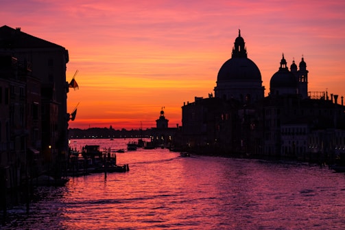 A warm-lit painting of Milan's historic canals at dusk, capturing the serene reflections on the water.