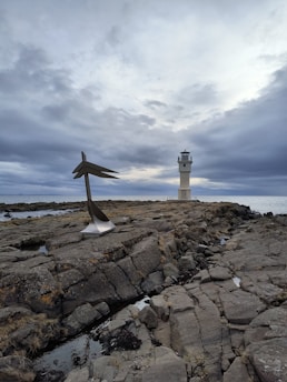 An abstract art design showing a lighthouse shining light through dark clouds.