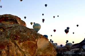 A vibrant sunrise with dozens of colorful hot air balloons floating over Cappadocia’s rocky landscape.