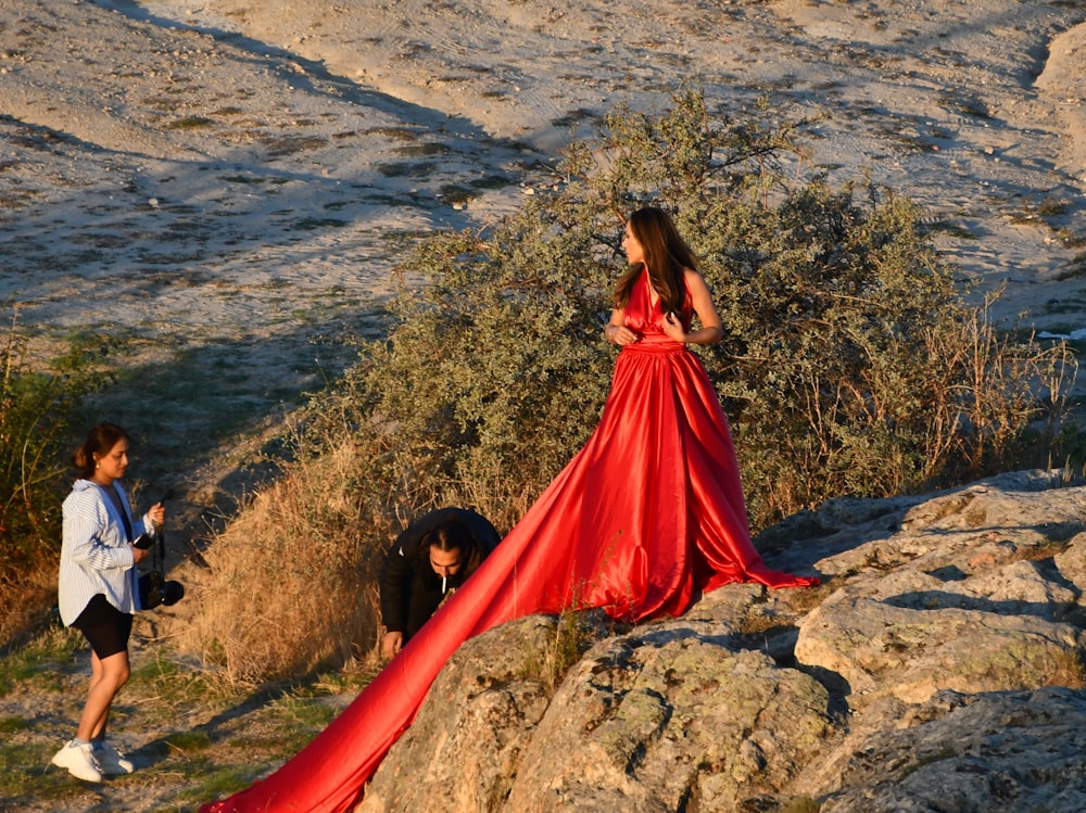 a woman in a long red dress standing on a hill