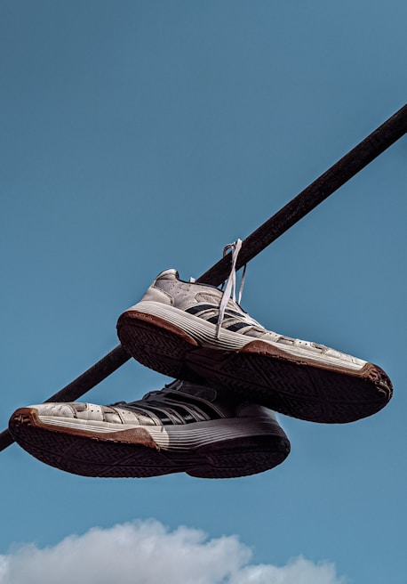 A pair of worn but charming socks hanging on a clothesline against a bright blue sky