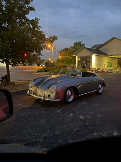 A gleaming vintage car parked on a cobblestone street under soft evening light, evoking nostalgia and elegance.