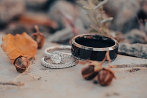 A close-up of the engagement rings resting on a rustic wooden surface surrounded by autumn leaves.