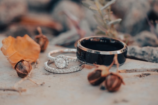 A close-up of sleek black and silver men's rings displayed on a wooden surface.