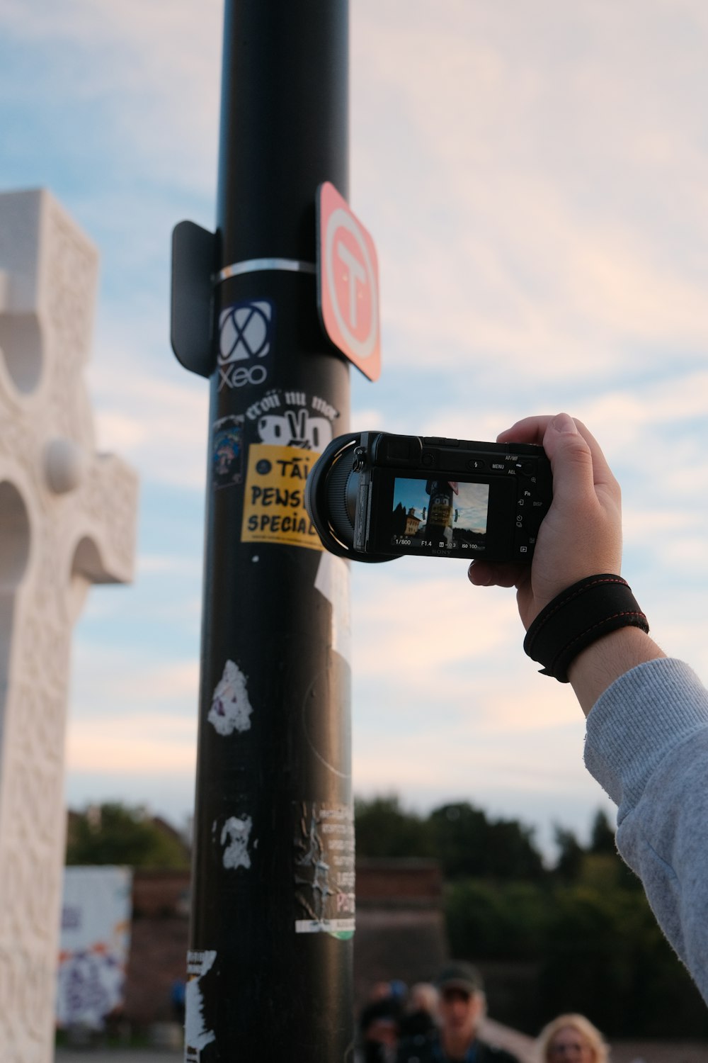 a person taking a picture of a cross on a pole