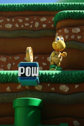 A cartoon-like scene with a yellow turtle character standing on grassy platforms within a layered, earthy background. In the foreground, there is a blue block with the word 'POW' and a green cartoon pipe.