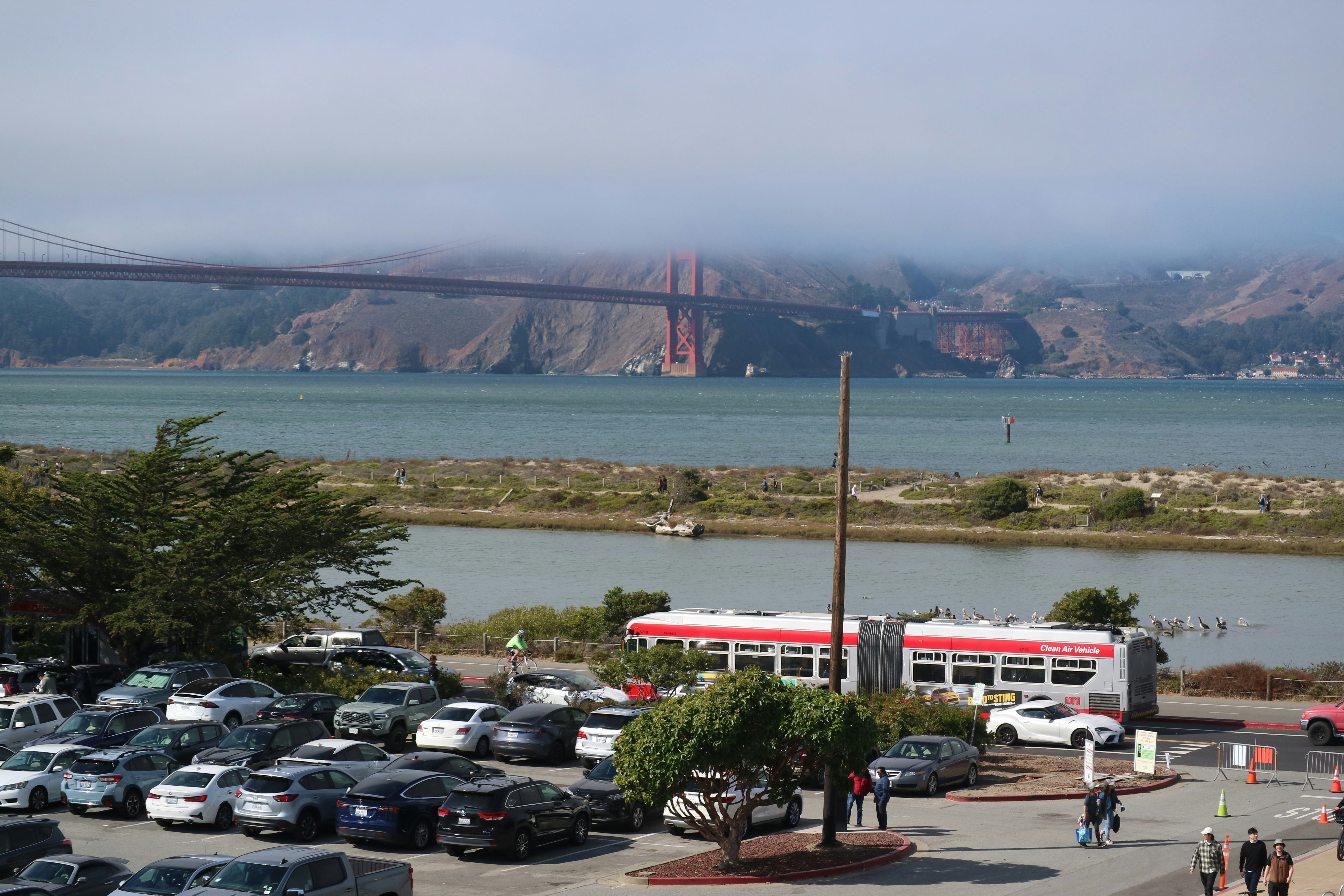 a red and white bus parked in a parking lot next to a bridge
