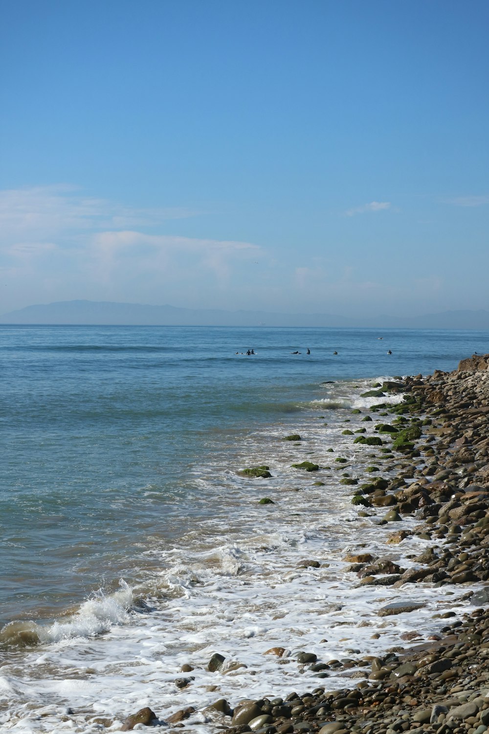 a group of people riding surfboards on top of a wave covered beach