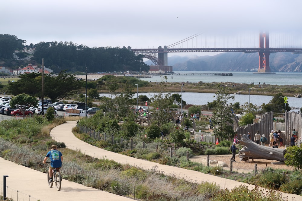 a man riding a bike down a path next to a river