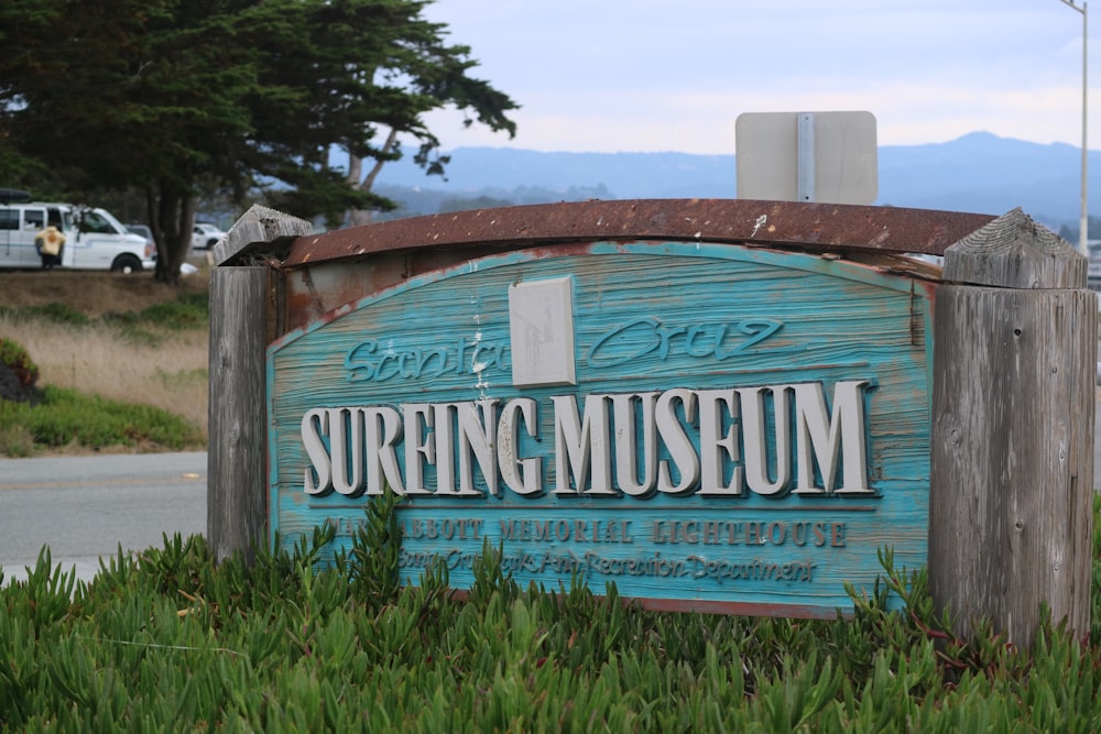 a wooden sign sitting in the grass next to a road