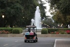 A gas-powered golf cart driving along a wooded golf course trail.