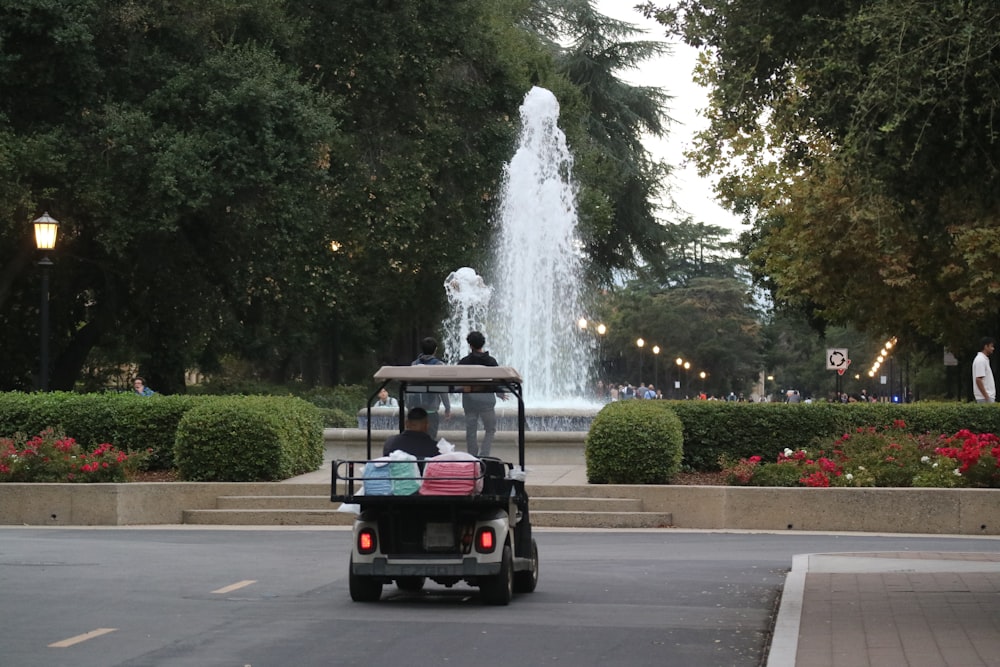 a man driving a golf cart in front of a fountain