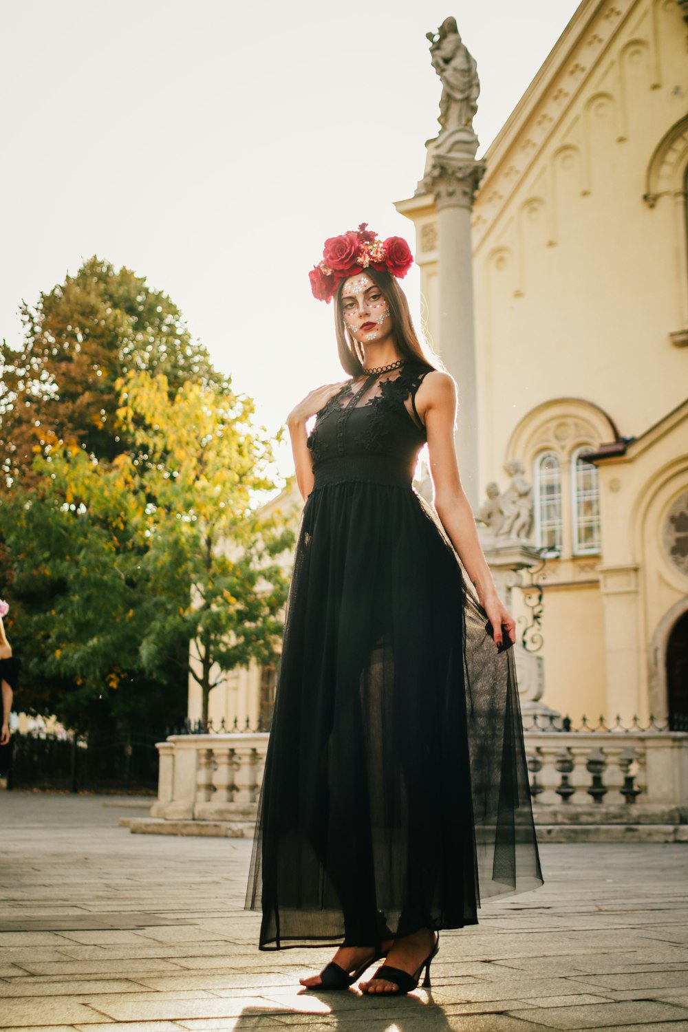 a woman in a long black dress standing in front of a building