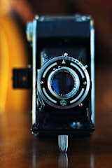 A close-up of a vintage camera on a wooden table.