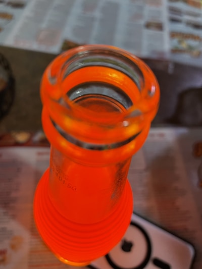 Close-up of a glass juice bottle filled with vibrant orange juice, highlighting the clarity and quality of the glass.