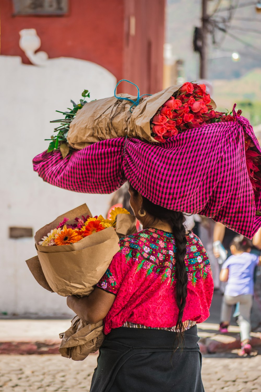 a woman carrying a bunch of flowers on her head