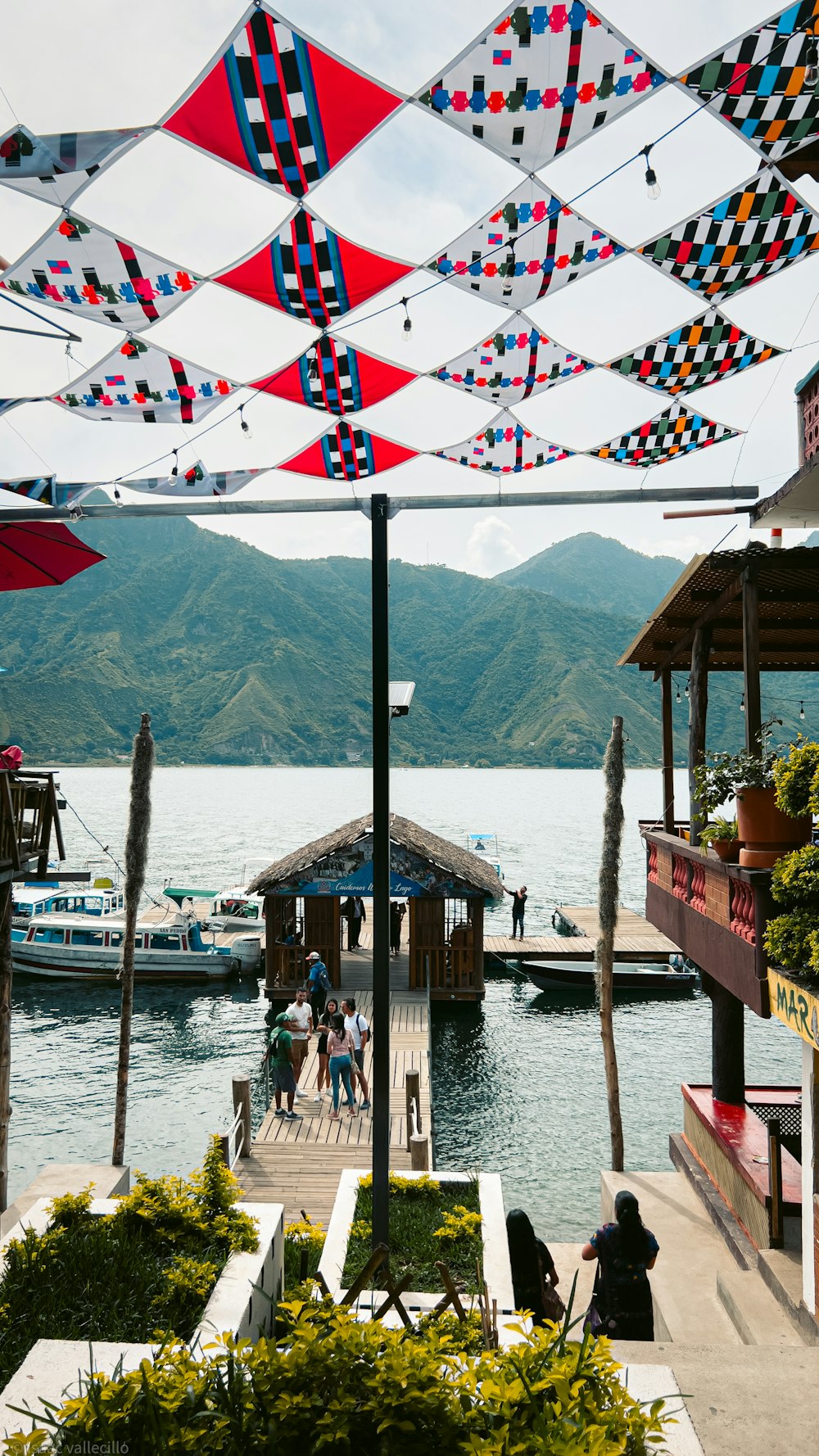 a group of people standing on a pier next to a body of water