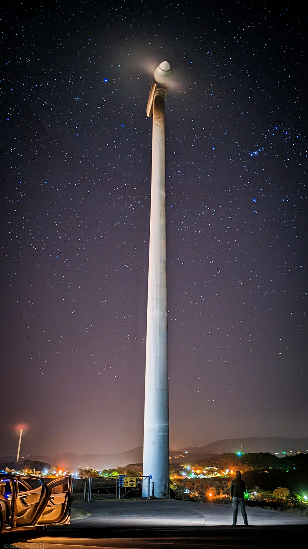 a man standing in front of a tall pole with a light on top of it