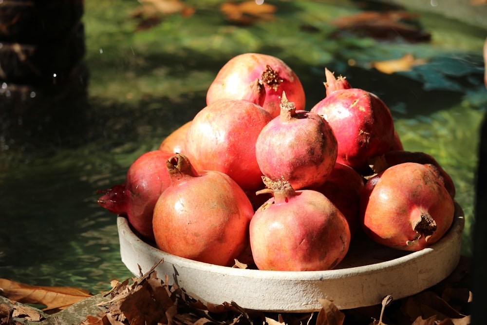 a bowl of pomegranates sitting on the ground