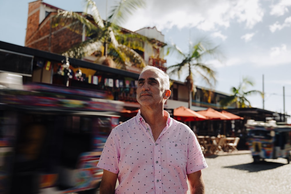 a man in a pink shirt is walking down the street