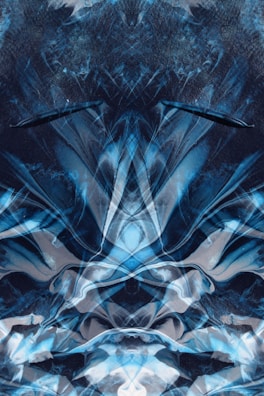 A digital abstract artwork featuring swirling patterns and shapes primarily in shades of blue, black, and white. The composition appears symmetrical with intricate layers and textures, creating a sense of depth and complexity.