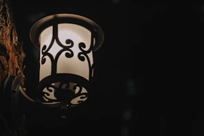 Close-up of a metal wall sconce casting soft light on a textured wall.