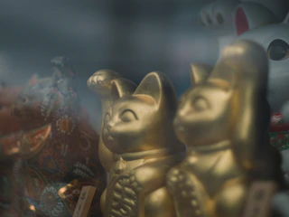 Close-up of a golden Maneki-neko charm with intricate fabric details