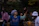 A joyful group of people playing drums together in a circle outdoors during sunset.