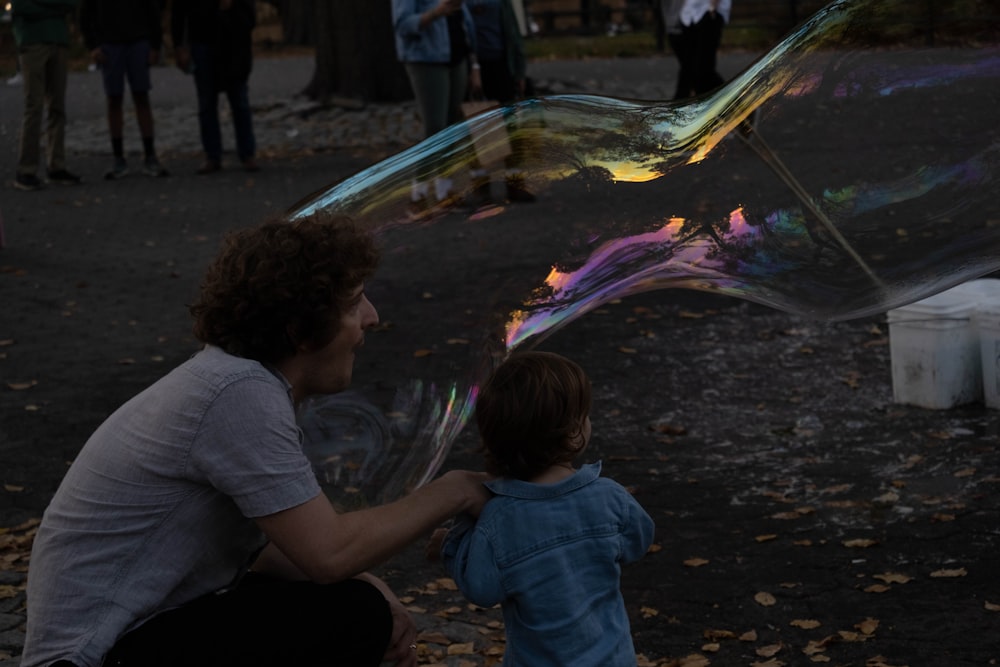 a man kneeling down next to a little boy