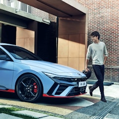 A modern car parked in a driveway with a family discussing insurance options.