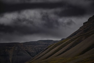 A dramatic landscape with rolling hills under a moody sky, captured at twilight.