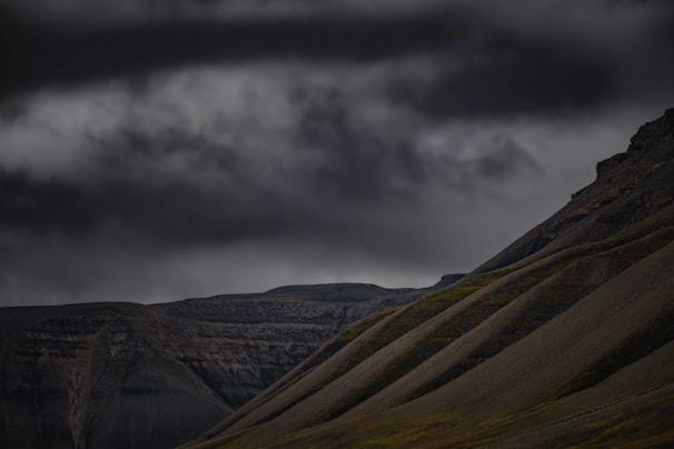 A dramatic landscape with rolling hills under a moody sky, captured at twilight.