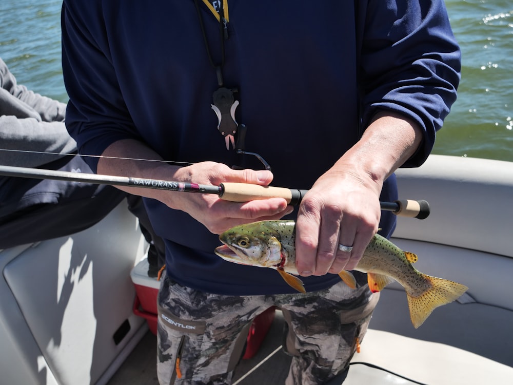 a man holding a fish while standing on a boat