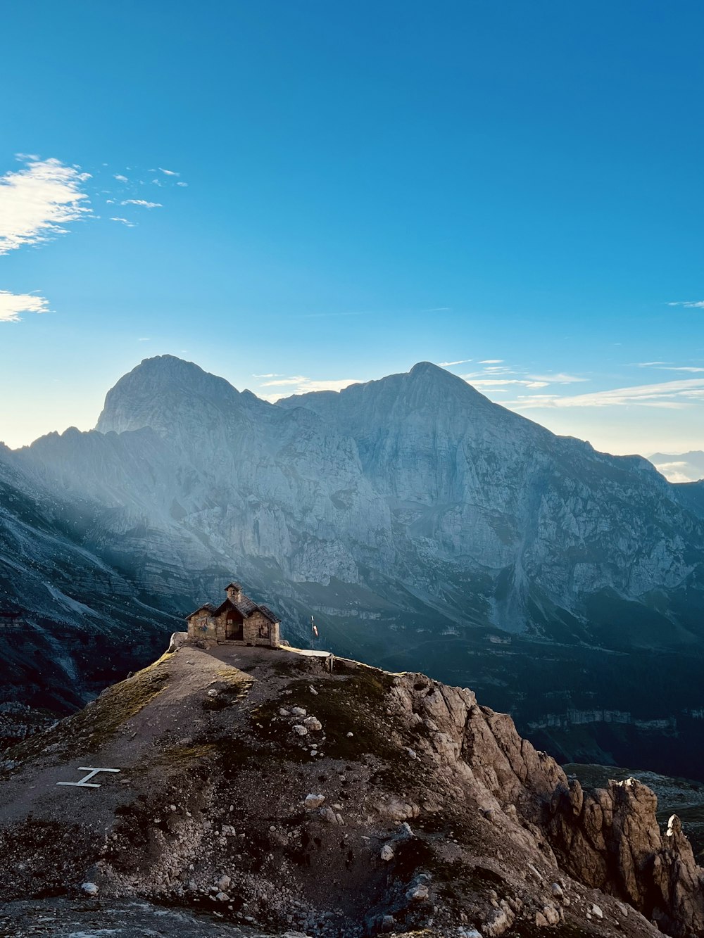 a house on top of a mountain with mountains in the background