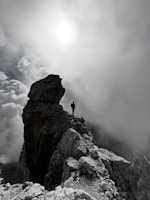 A lone hiker standing on a mountain peak at sunrise, embracing solitude.