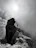 A candid shot of a hiker reaching a mountain summit at sunrise, with vibrant colors and dynamic clouds.