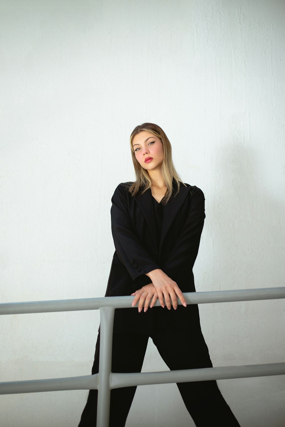 a woman in a black suit leaning on a rail