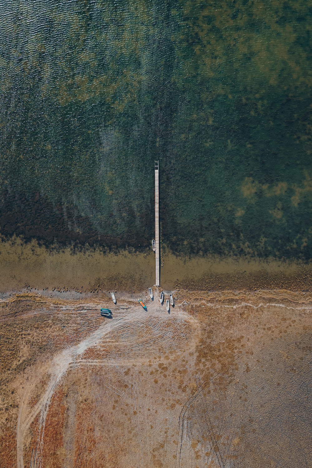an aerial view of a dirt road and a tall pole