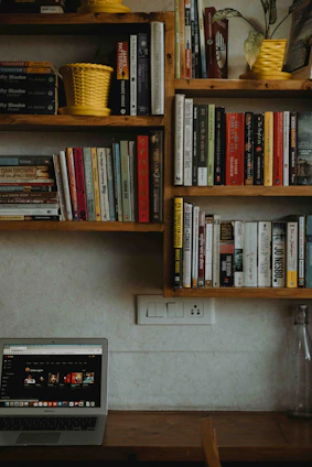 A cozy home office with shelves filled with various retail products and a laptop displaying the varejovivo website.