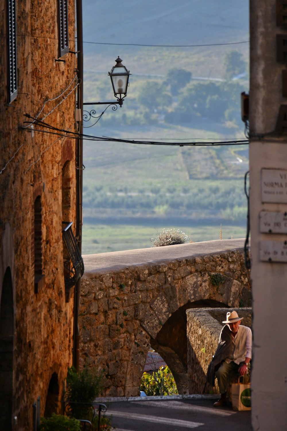 a man sitting on a stone wall next to a street