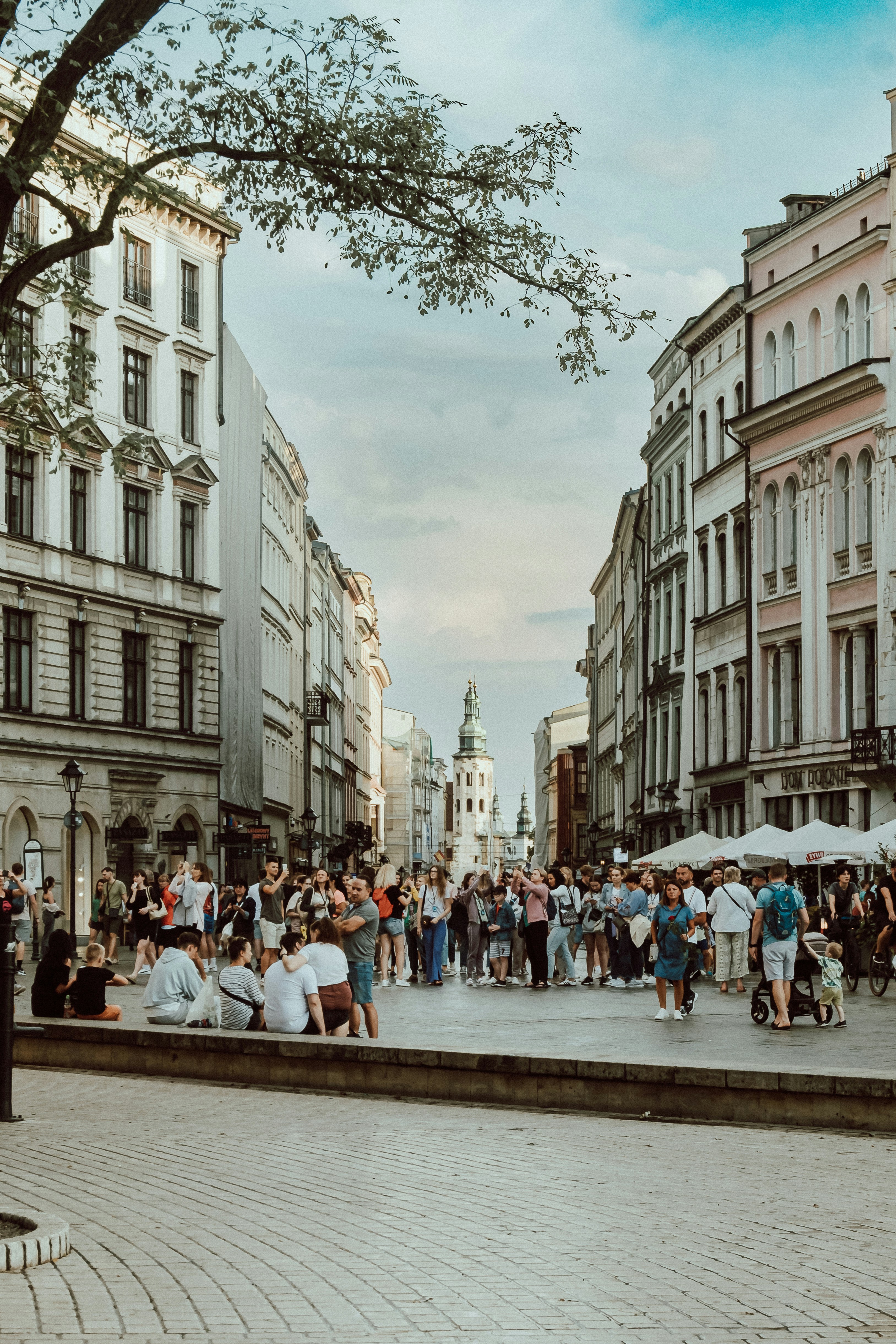 a crowd of people walking down a street next to tall buildings