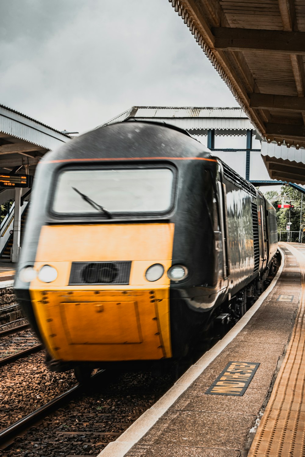 a yellow and black train pulling into a train station