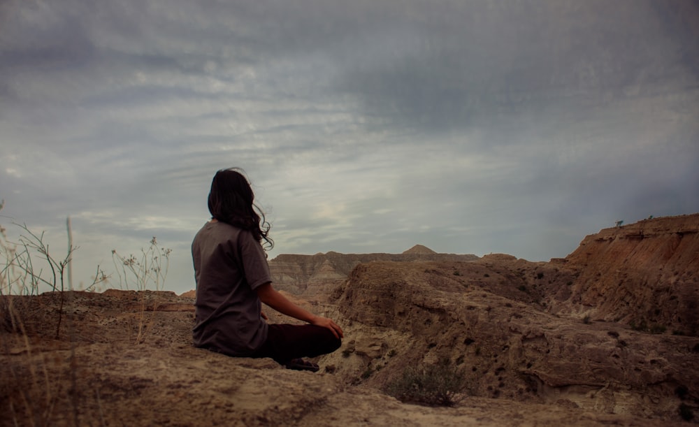 uma mulher sentada no topo de uma colina de terra