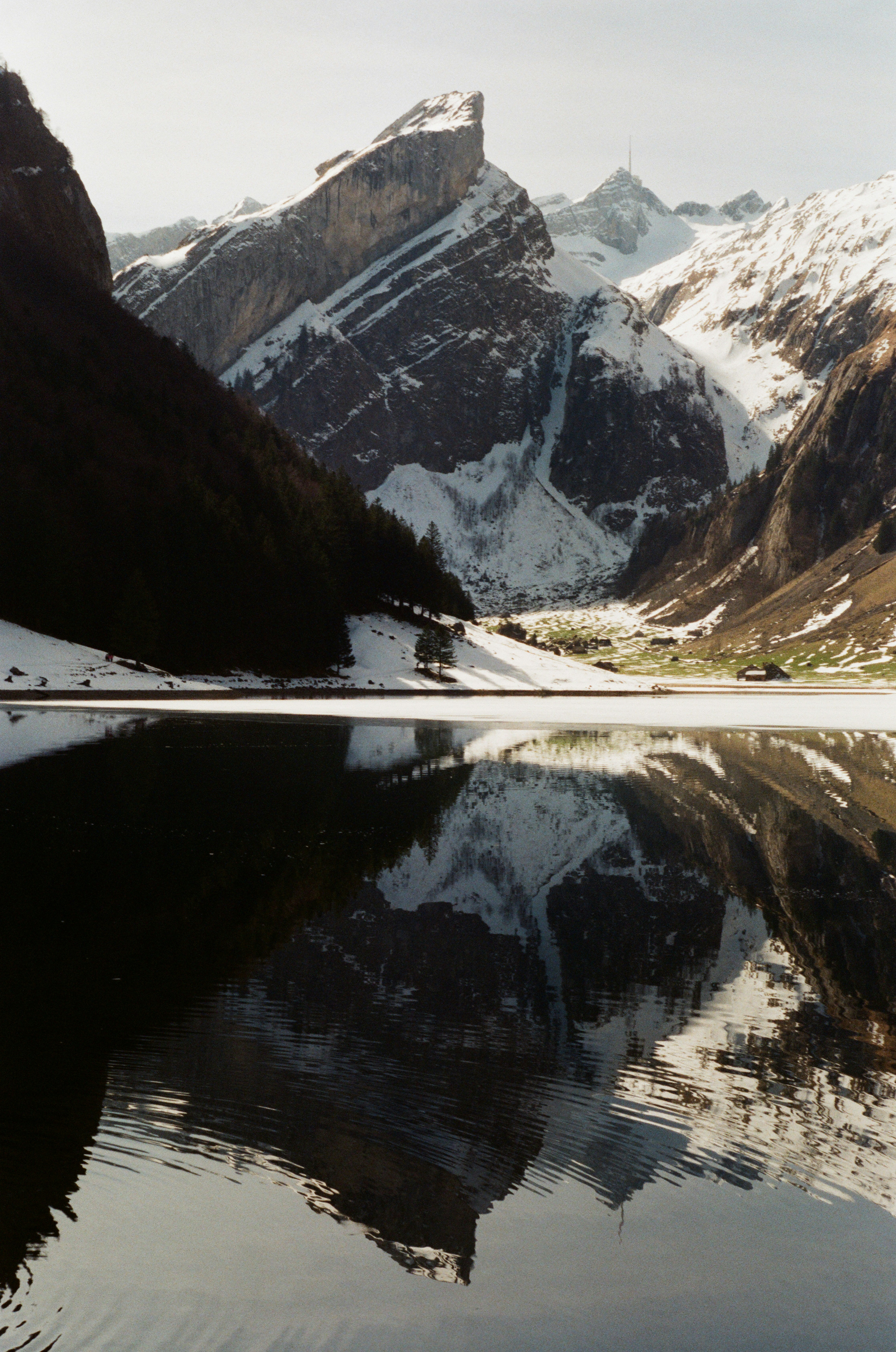 uma cordilheira se reflete na água parada de um lago