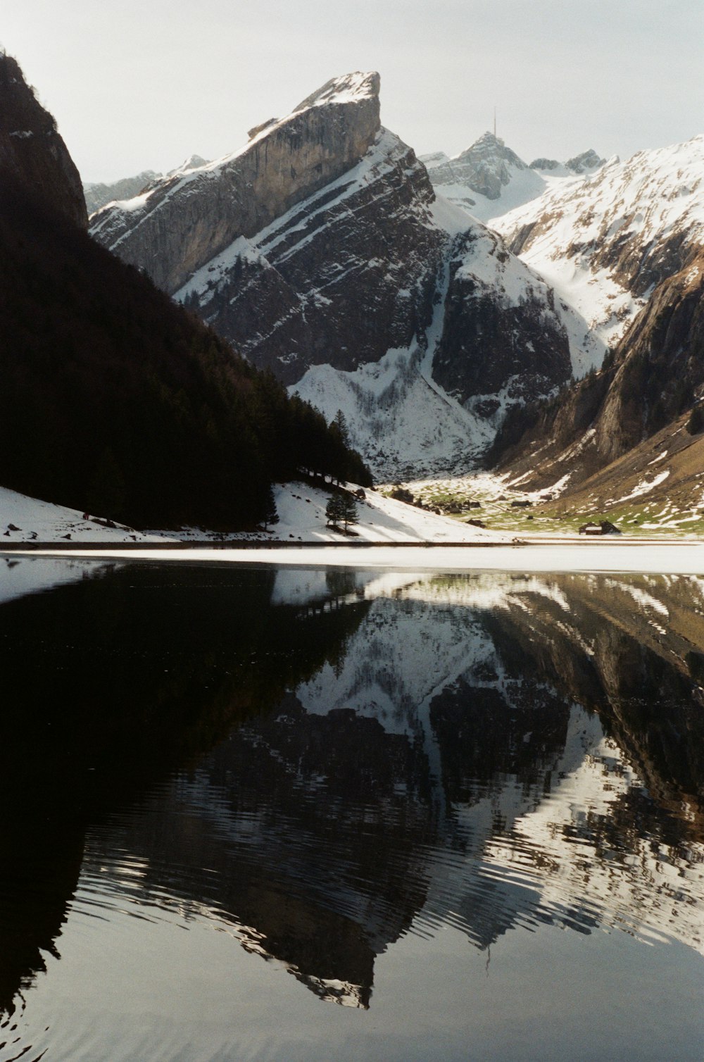 a mountain range is reflected in the still water of a lake