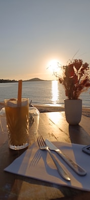 A peaceful seaside terrace with pastel cushions and a bottle of le coquers on a small table.
