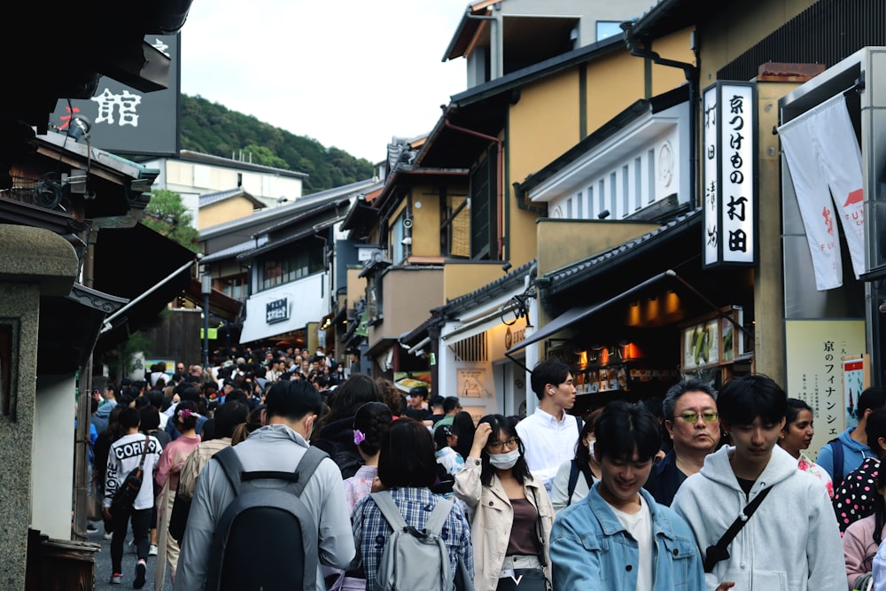 a crowd of people walking down a street next to tall buildings