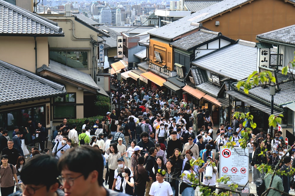 a crowd of people walking down a street next to tall buildings