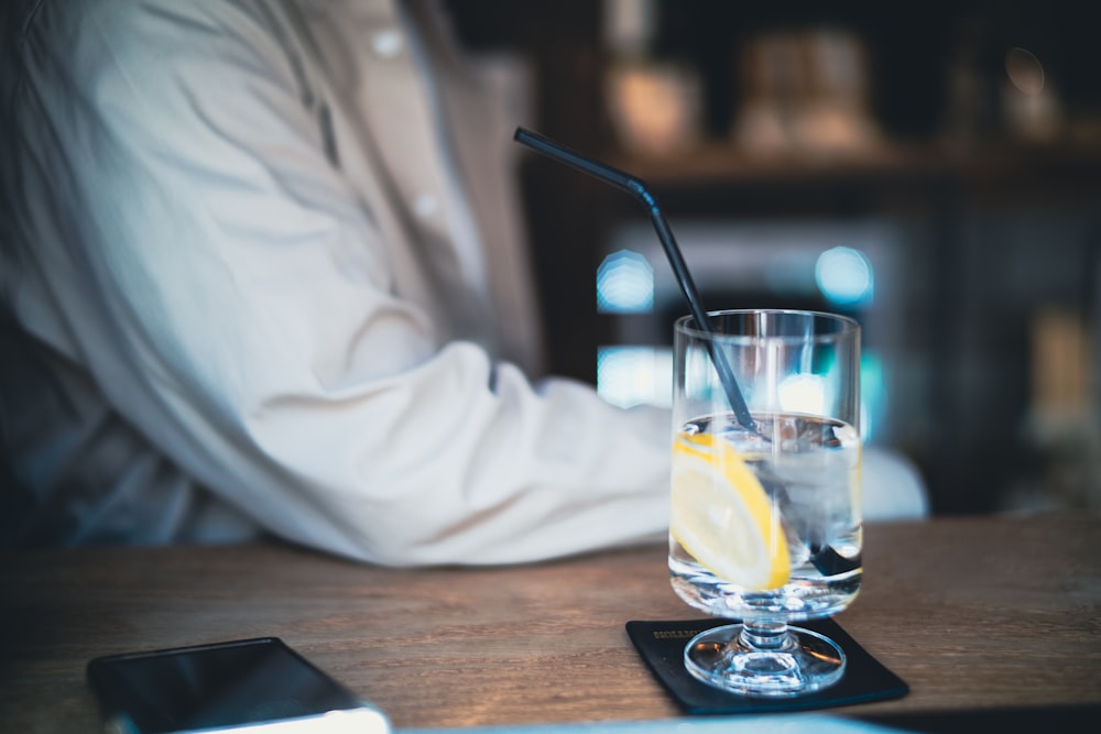 a person sitting at a table with a drink and cell phone