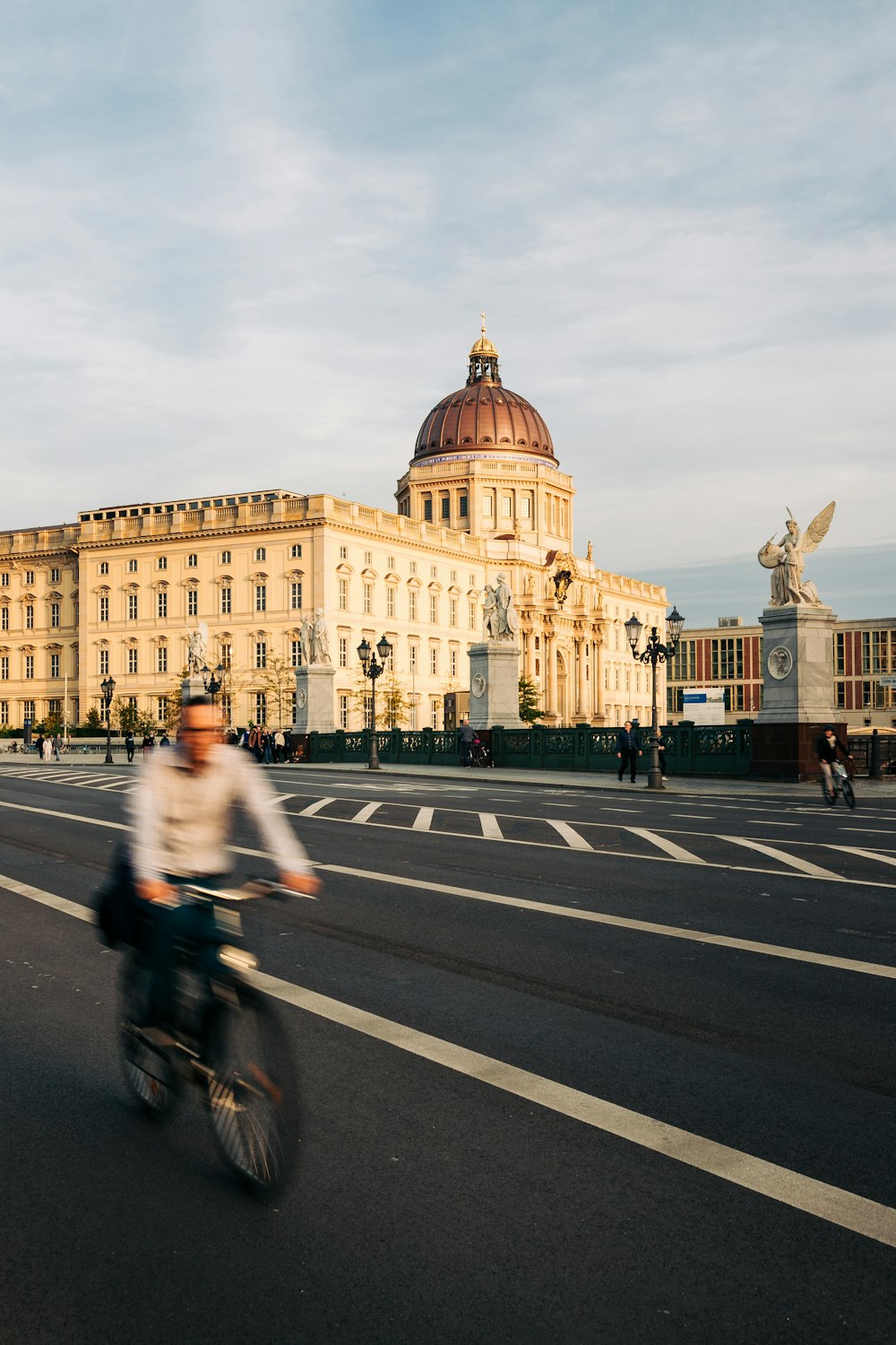 Un hombre andando en bicicleta por una calle junto a un edificio alto